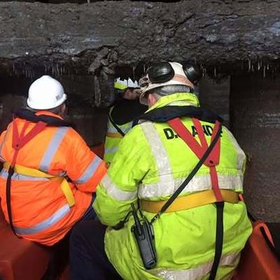 Crew in high-visibility clothing working beside masonry from the boat