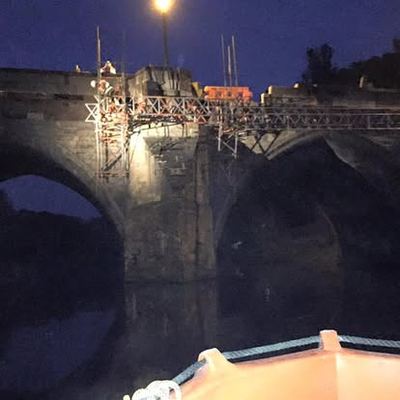 View from the boat towards illuminated bridge works at night