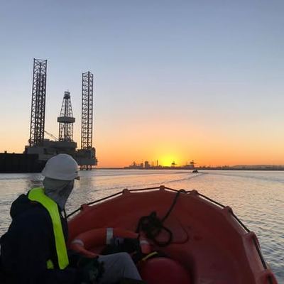 Crew and orange safety boat on the water at sunset